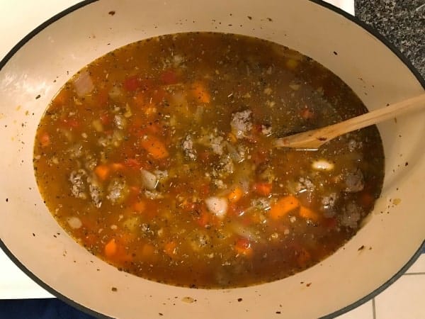 broth, tomatoes, carrots and Italian sausage in Dutch oven