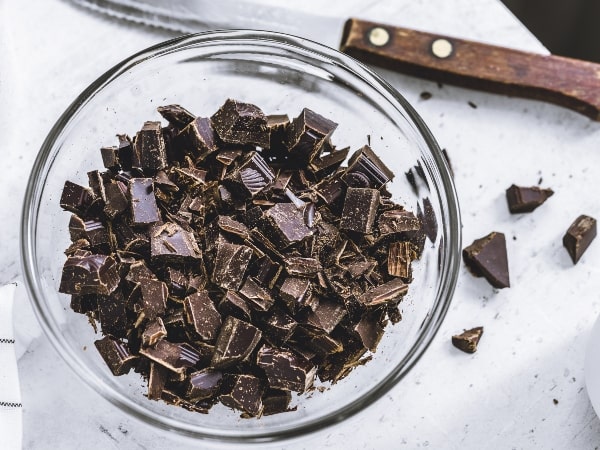 dark chocolate, a nutrient-dense food, chopped up in a bowl and a knife on the table