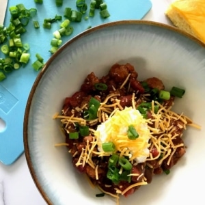 Slow Cooker Turkey Chili in a bowl with green onions and cornbread on the side.