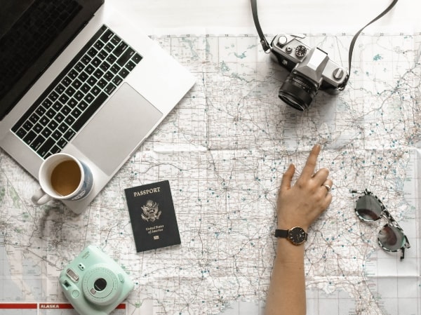 how to plan your next vacation, picture of map, passport, laptop, and camera