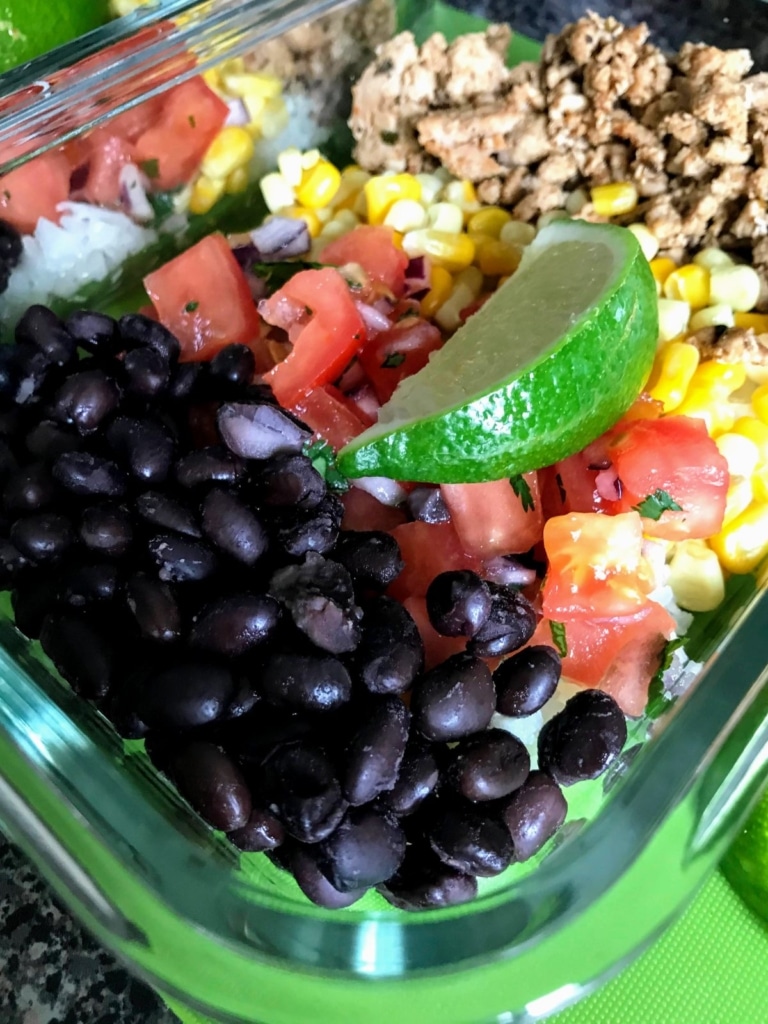 easy healthy burrito bowls with black beans, tomatoes, corn, ground turkey and slice of lime on top