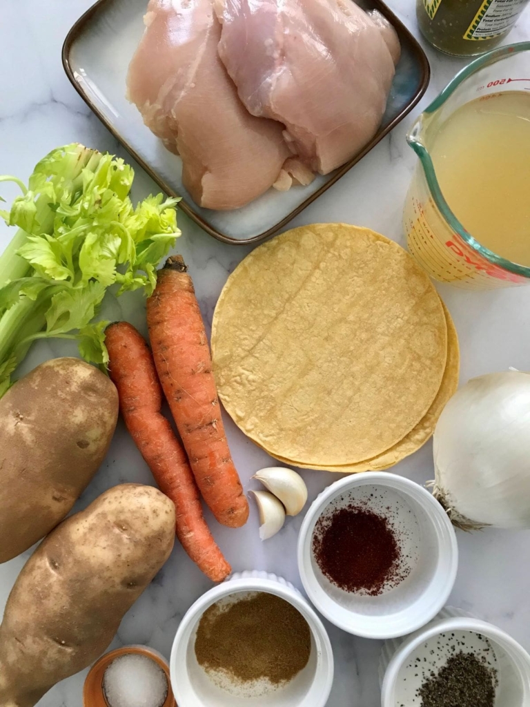Ingredients for Mexican style chicken stew chicken breast, tortillas, chicken broth, carrots, celery potatoes, garlic, onion, and spices