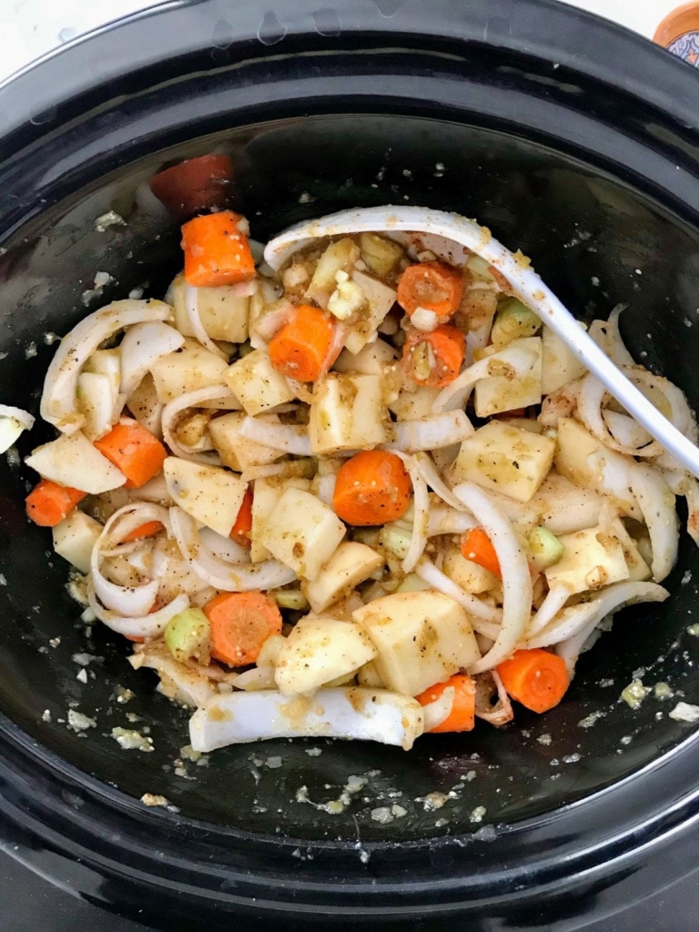 raw potatoes, carrots, and onions in a slow cooker