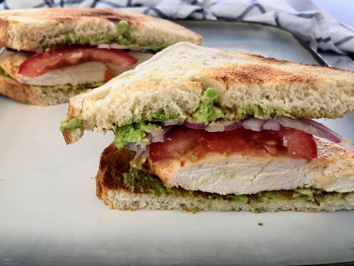 chicken avocado sandwich with sourdough bread on a plate.