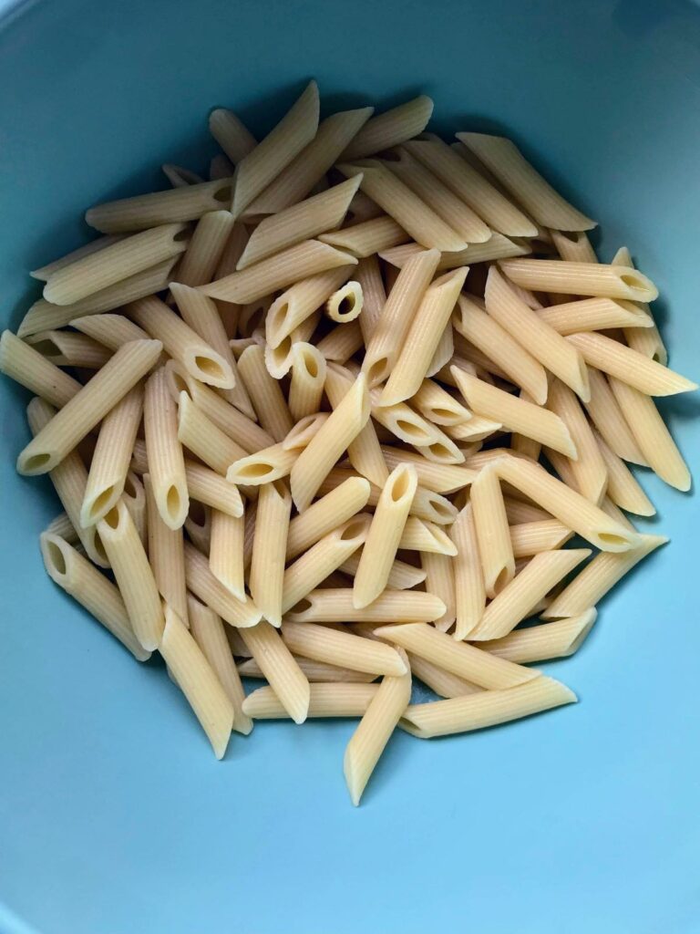 cooked penne pasta in a blue bowl.