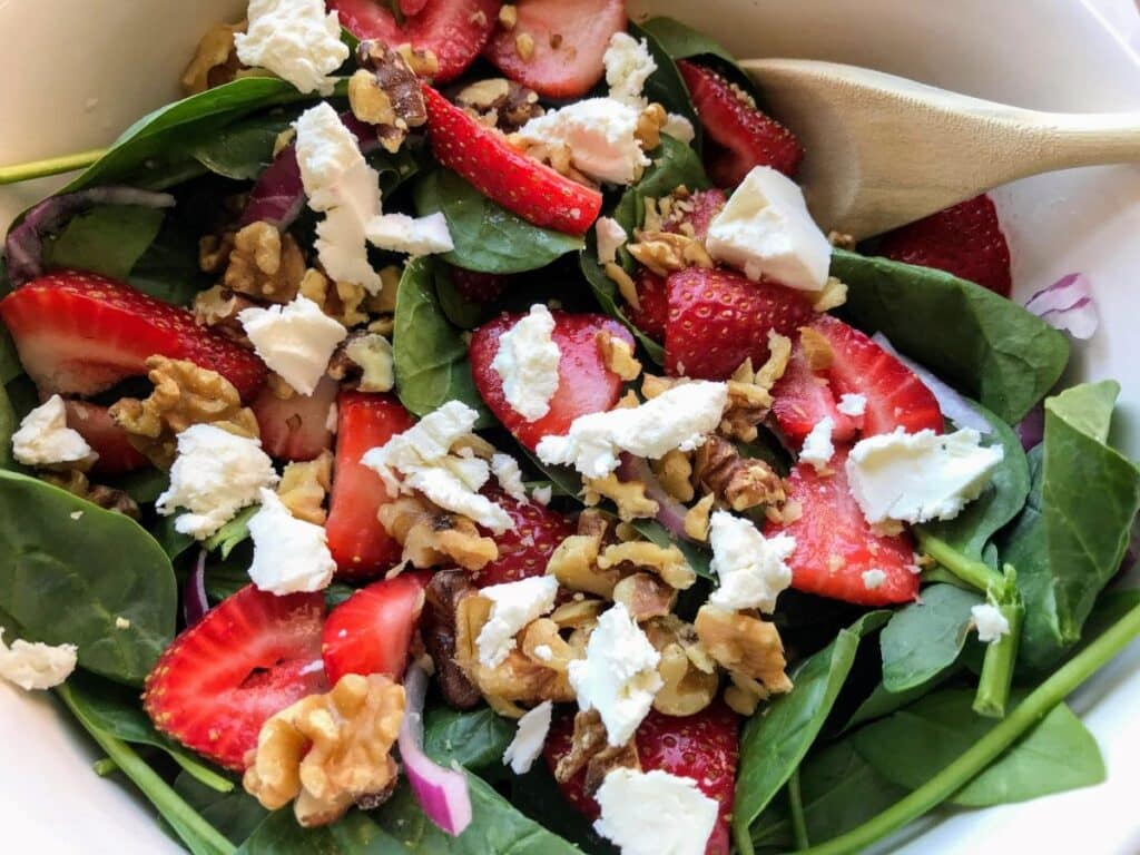goat cheese on top of strawberries, spinach, and walnuts.