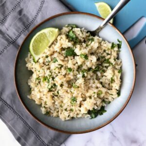 Cilantro lime brown rice in a bowl with a lime wedge.